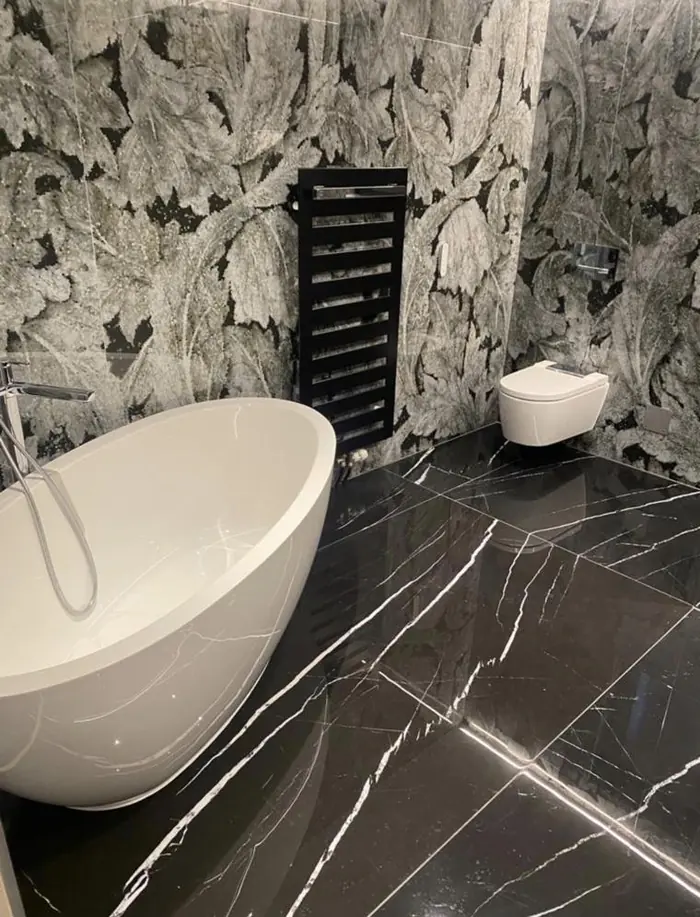 Baignoire îlot blanche, sol en marbre noir et mur en mosaïque végétale