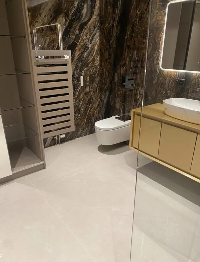 Salle de bain avec mur effet pierre brune et WC suspendu