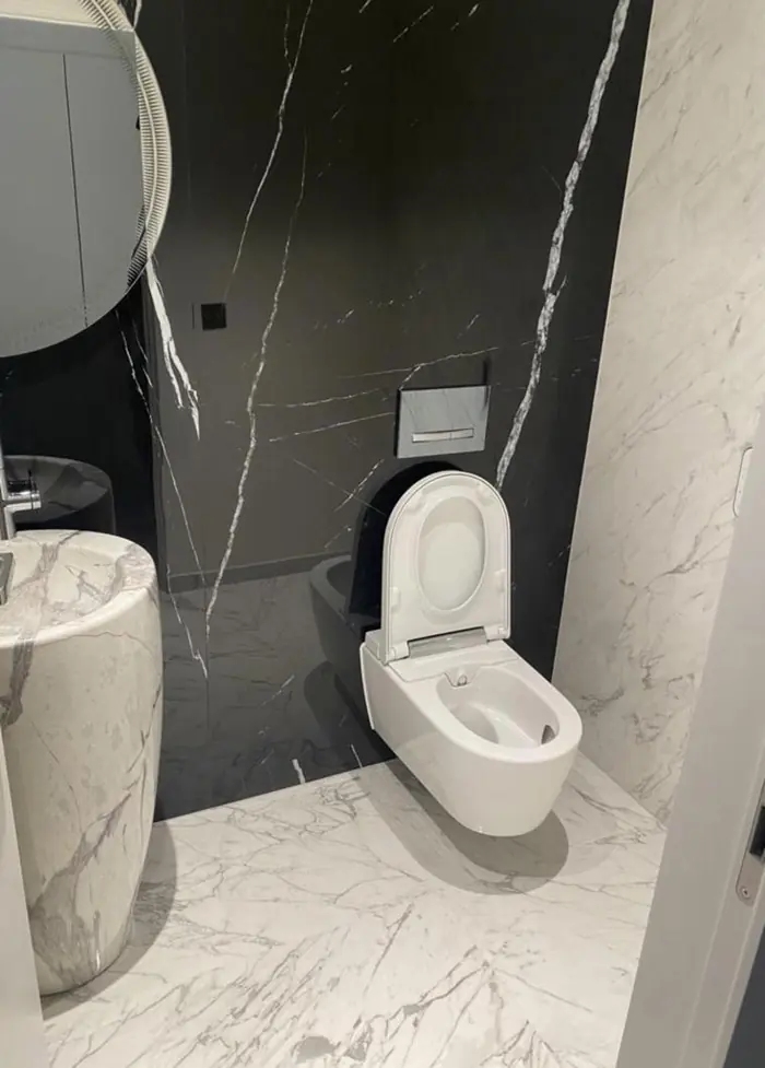 WC suspendu sur mur en marbre noir avec lavabo colonne en marbre blanc